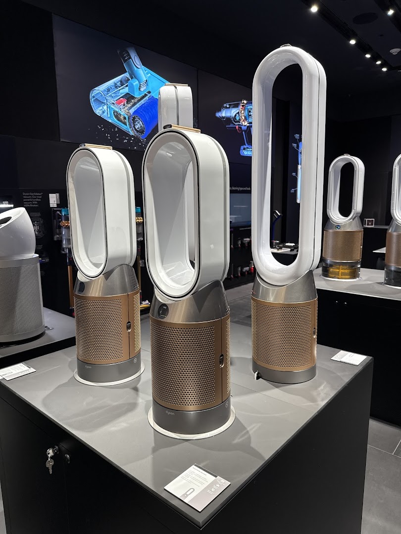 Dyson air purifiers and vacuum cleaners are displayed in a modern retail store setting.