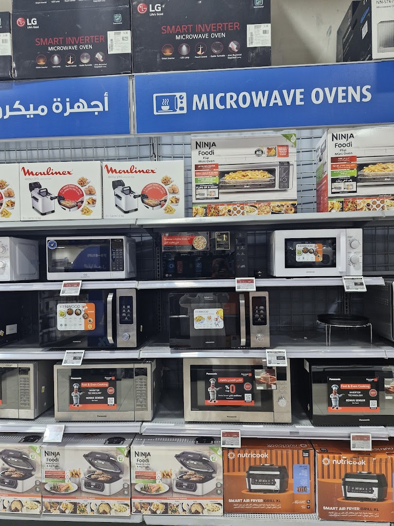 Shelves stocked with various microwave ovens and air fryers from brands like LG, Kenwood, Panasonic, and Ninja.