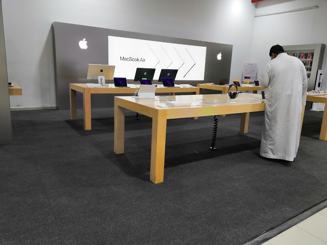 A person in traditional attire browsing Apple products in a modern electronics store.