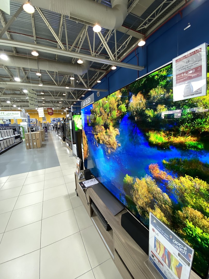 An aisle in an electronics store featuring large LG OLED televisions and other appliances.