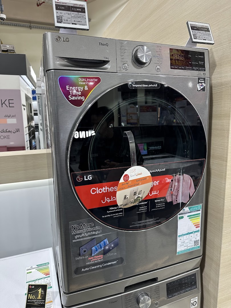 A silver LG ThinQ washing machine with a large glass door and various feature stickers.