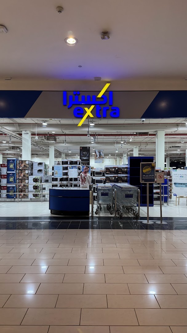 The entrance to an eXtra electronics store with a prominent sign and shopping carts.