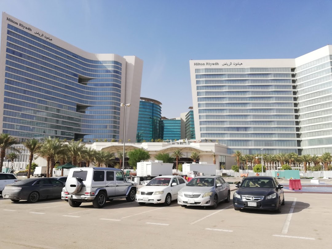 Modern buildings with cars parked in front under a clear blue sky.