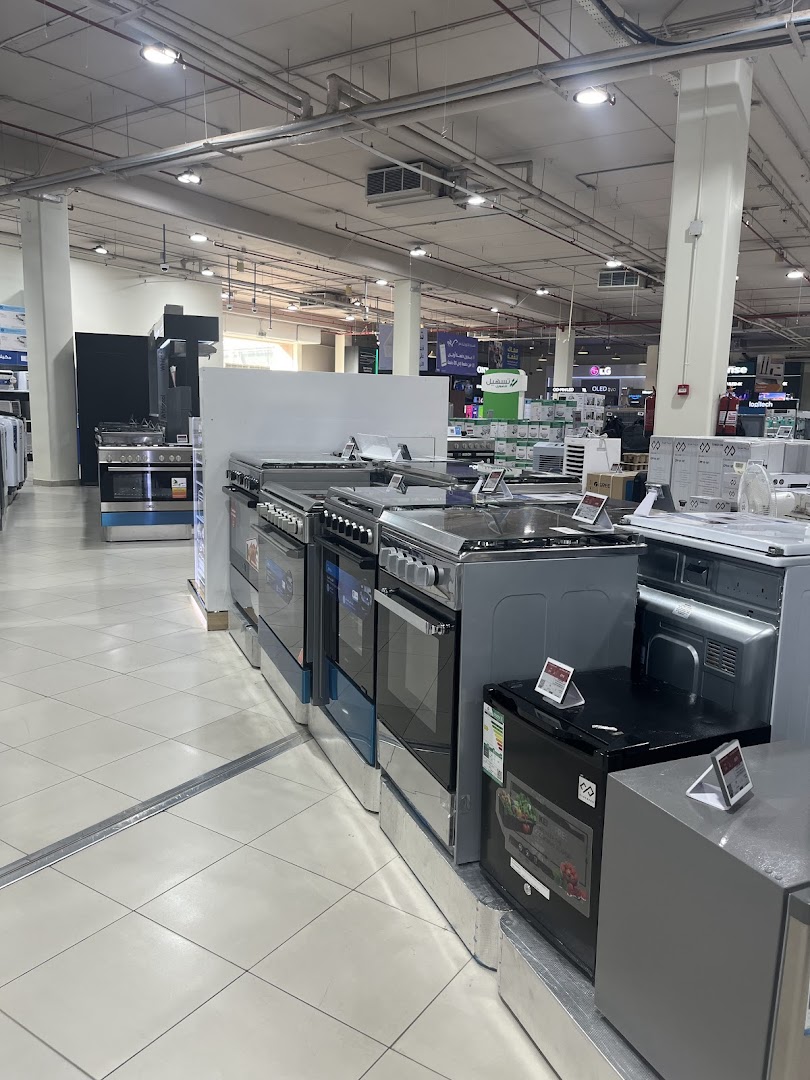 A wide shot of a retail store aisle showcasing various kitchen appliances like ovens and refrigerators.