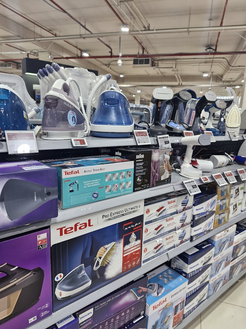 A display of various steam irons and garment steamers from brands like Tefal, Philips, and Braun.