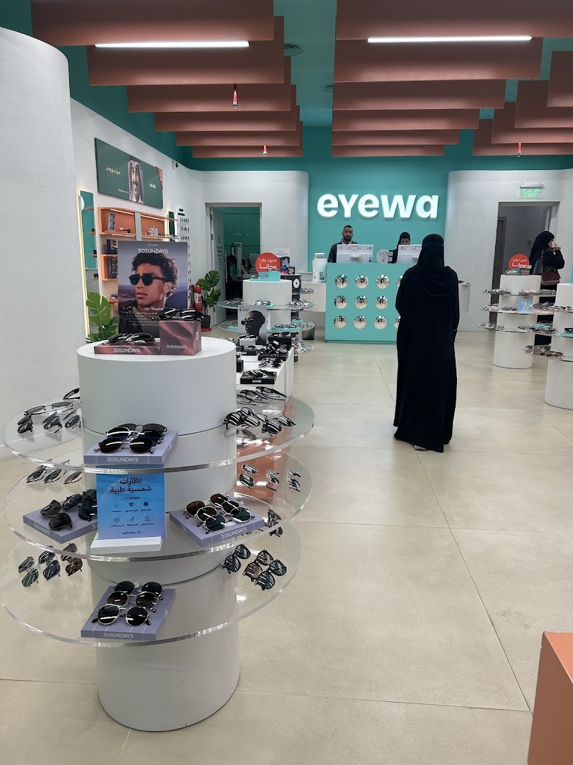 Interior view of an Eyewa store showcasing sunglasses on display stands and a counter.