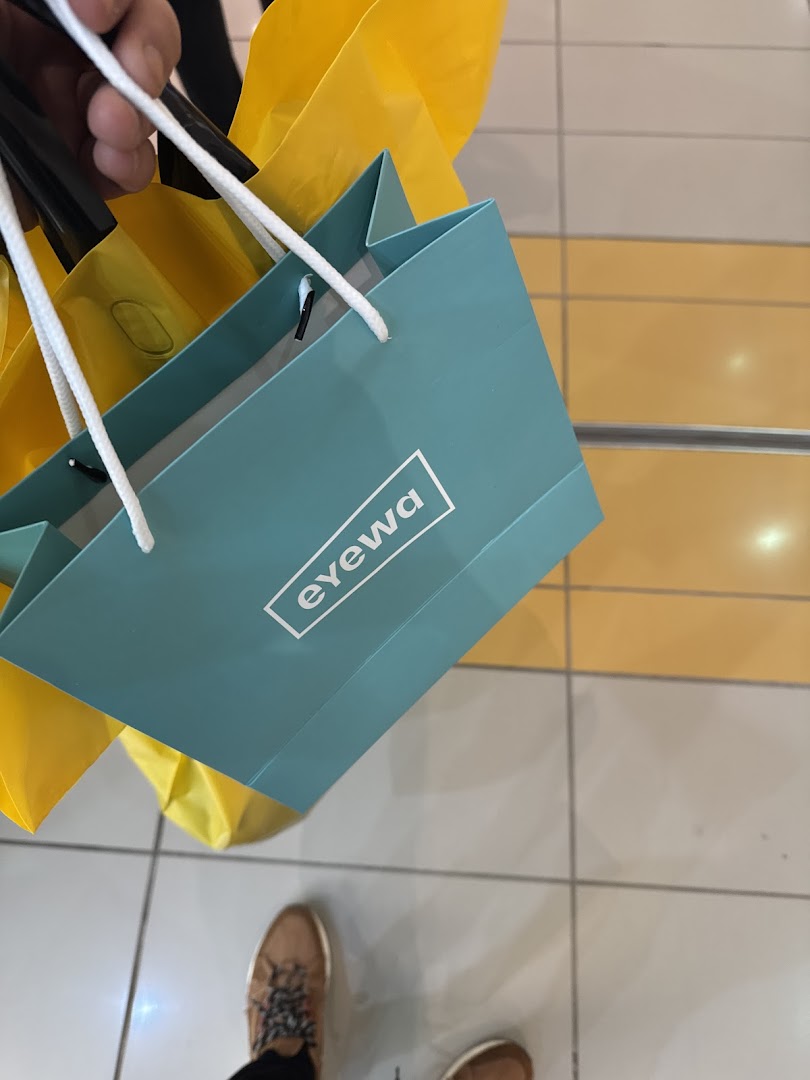 A person holding shopping bags from eyewa, with other shopping bags in the background.