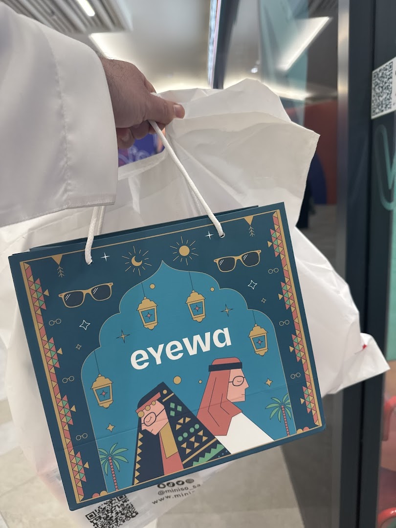 A person in traditional attire holds a shopping bag from Eyewa.