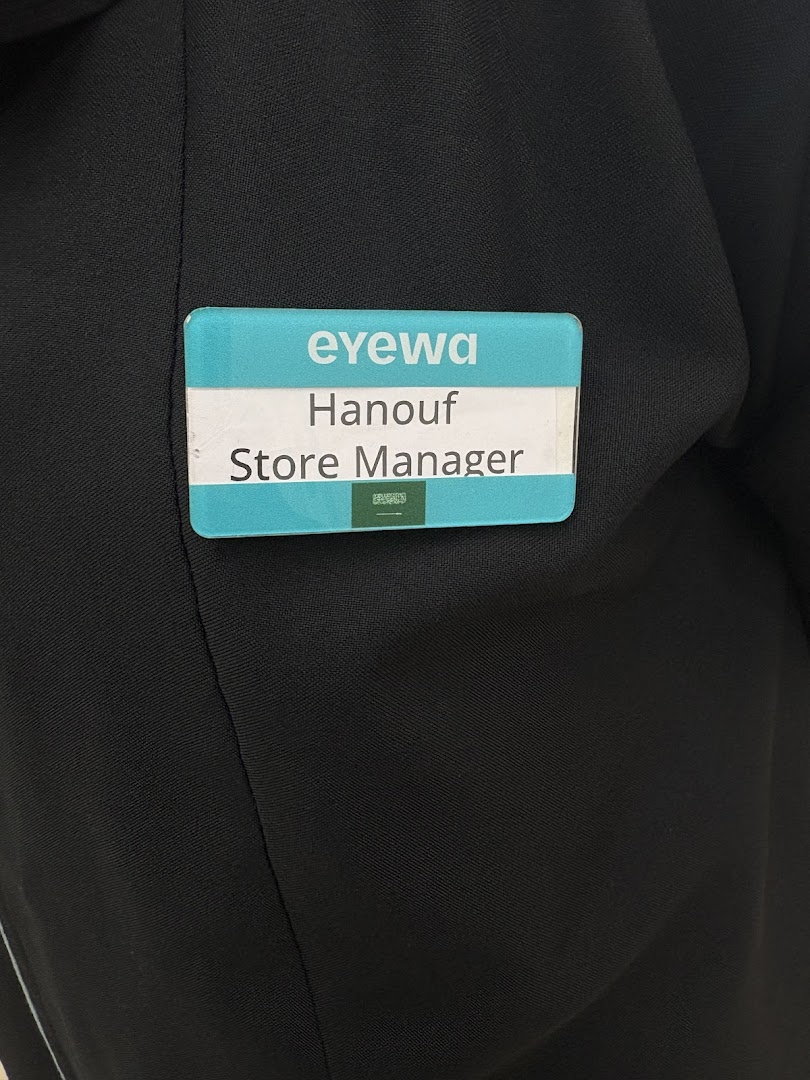 A close-up of a name tag on a black uniform, identifying the wearer as Hanouf, Store Manager.