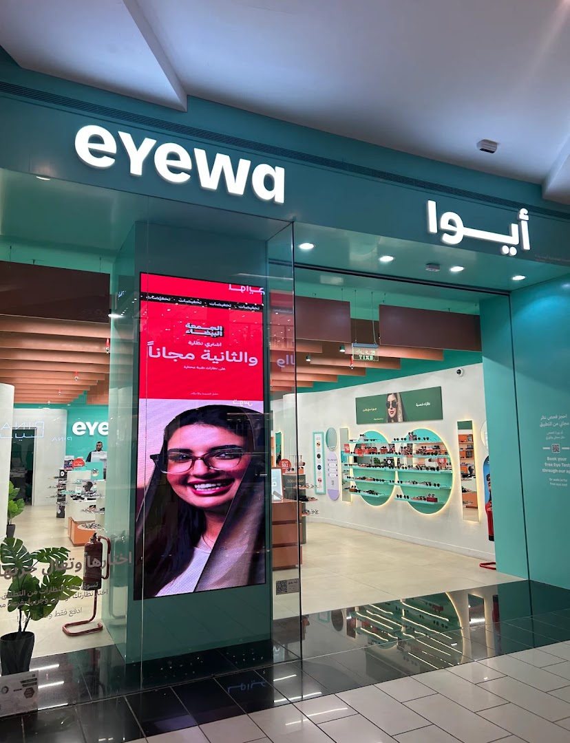 The modern storefront of Eyewa, an optical shop, featuring a large digital display and a wide selection of eyewear.