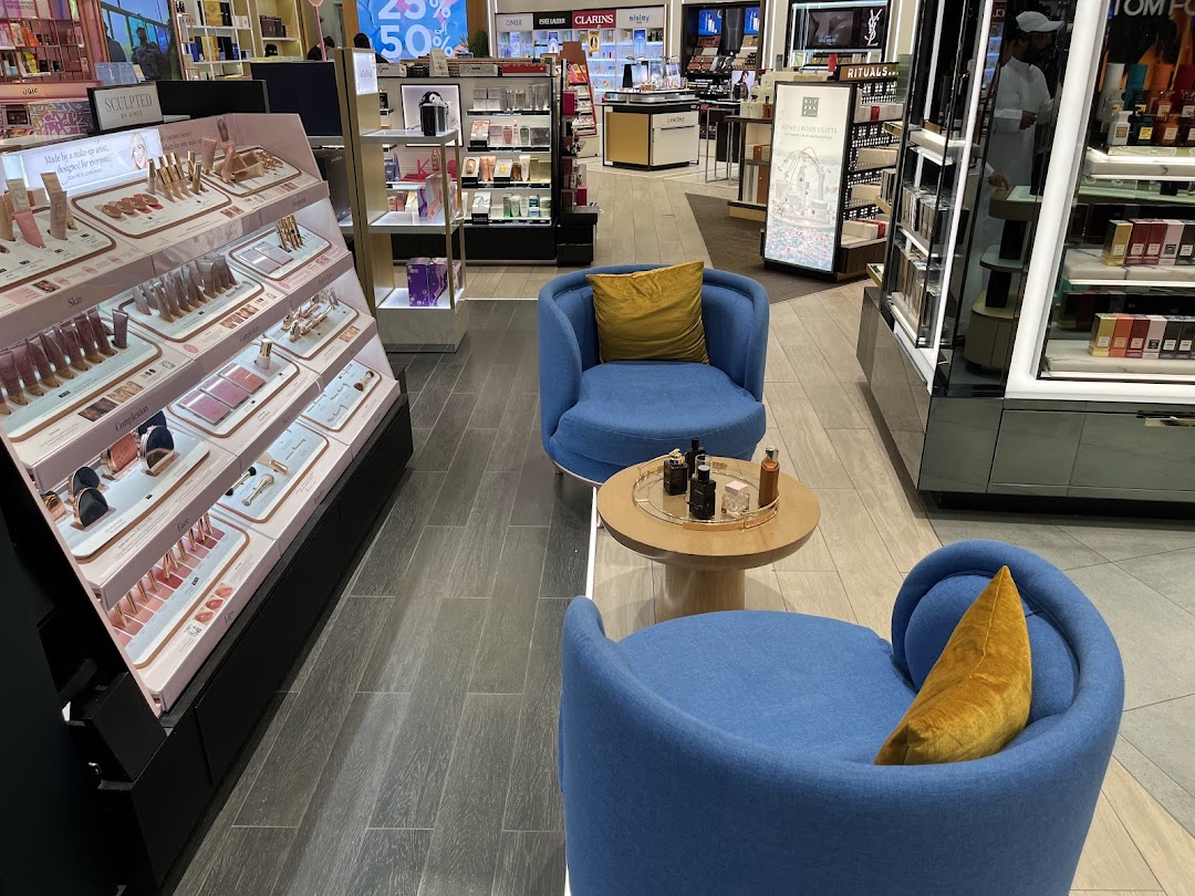 Interior of a beauty store with makeup displays, seating, and perfume counters.