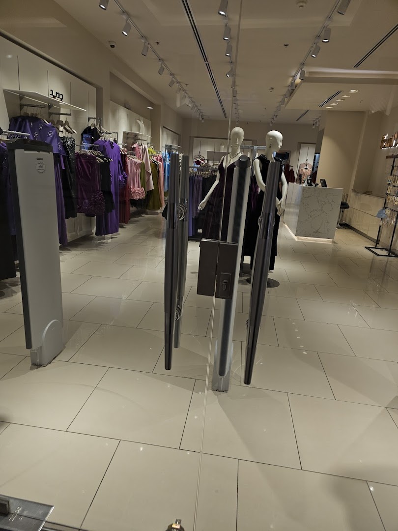 Interior view of a clothing store with mannequins and racks of dresses.