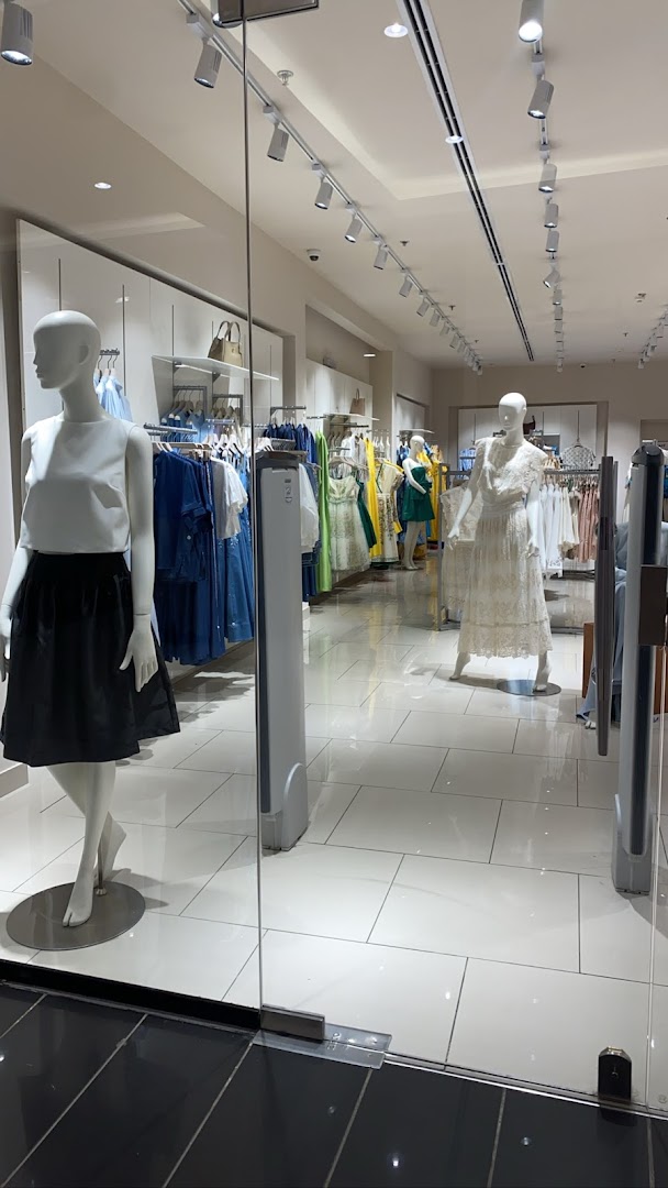 View of a Femi9 clothing store interior with mannequins and racks of apparel.