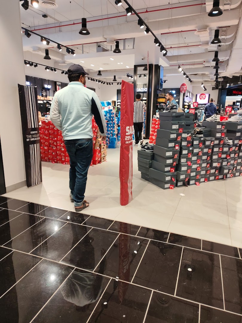 A man walks through a Foot Locker store filled with shoe boxes and displays.