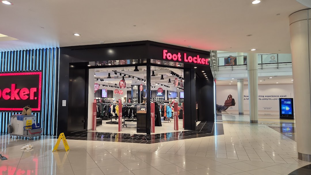 The Foot Locker store entrance with clothing and shoes displayed inside.
