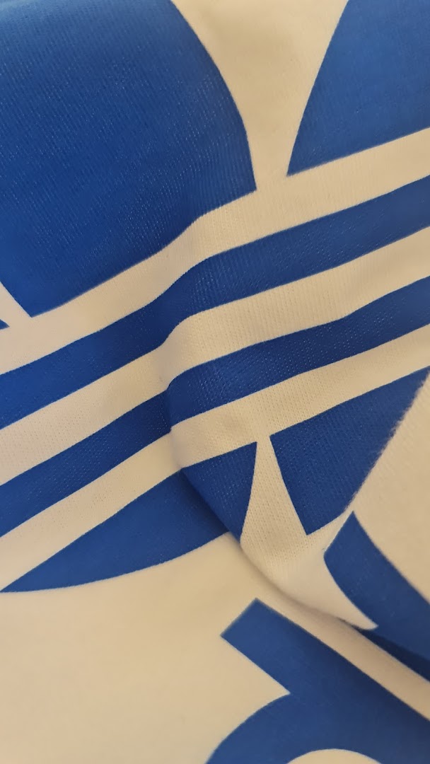 Close-up of a white fabric with a blue Adidas logo and stripes.