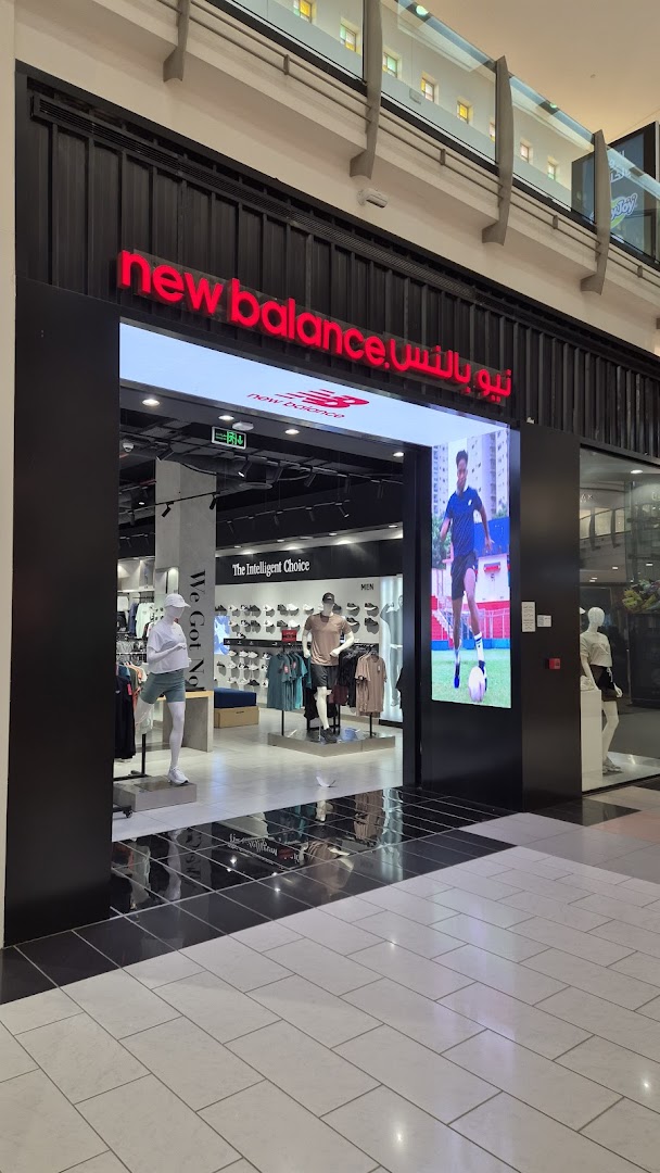 The entrance to a New Balance store, featuring mannequins and displays of athletic wear.