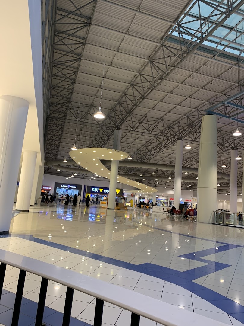 A wide view of a modern shopping mall interior with shops and people.
