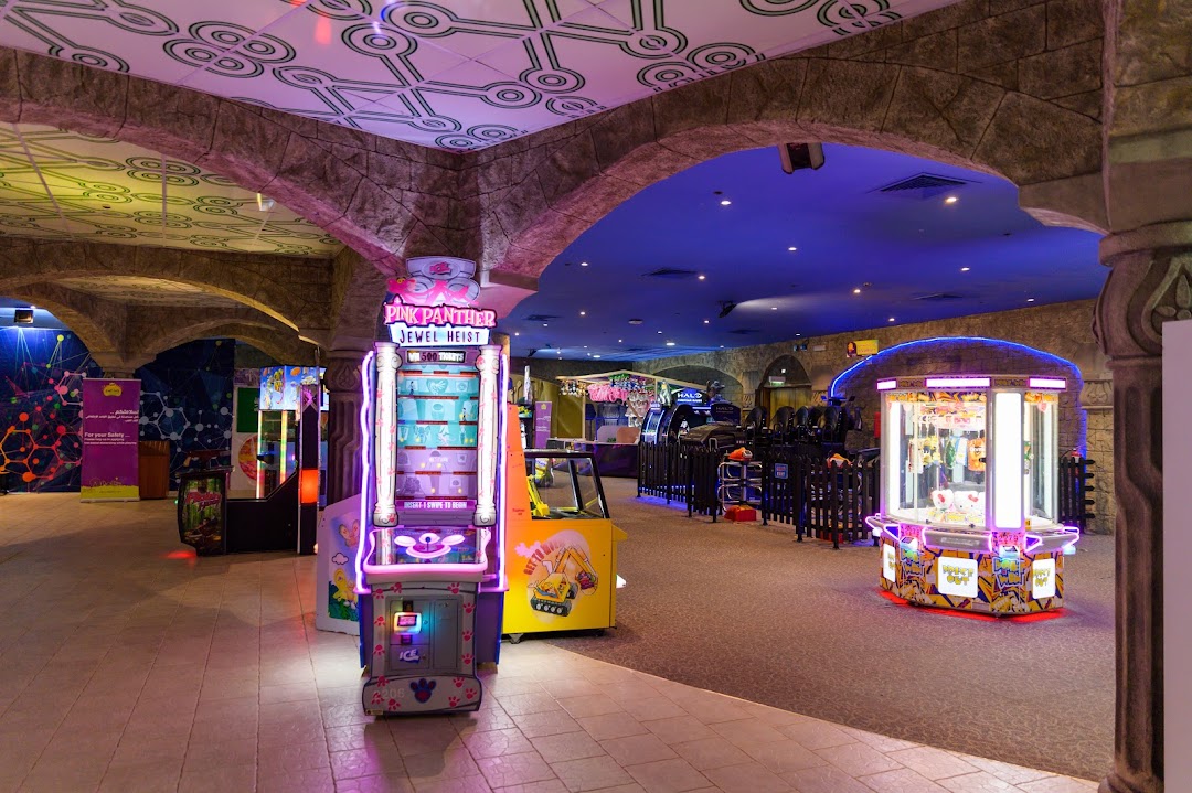 Interior view of an arcade with various game machines, including claw machines and video games.