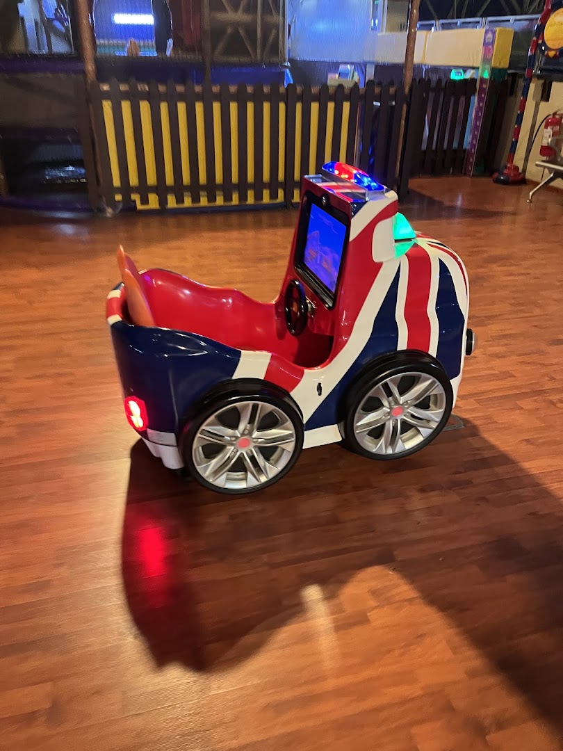 A Union Jack themed ride-on car with flashing lights on a wooden floor.