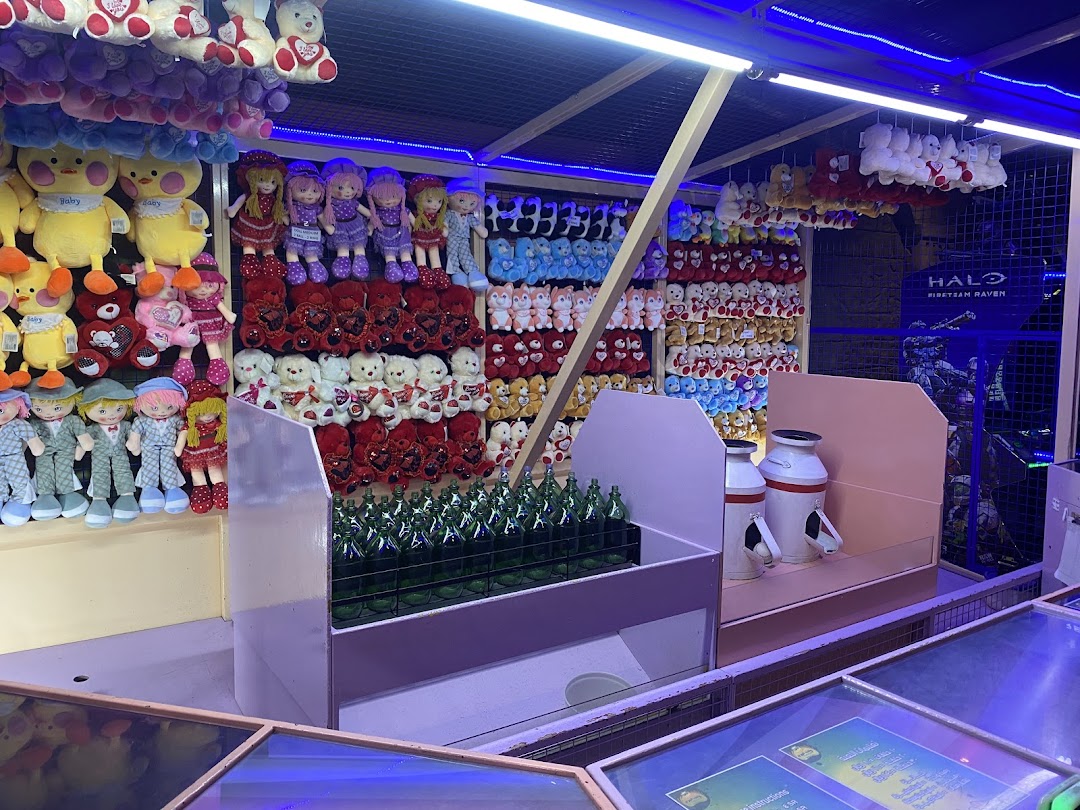 A colorful stall filled with plush toys and a bottle toss game.