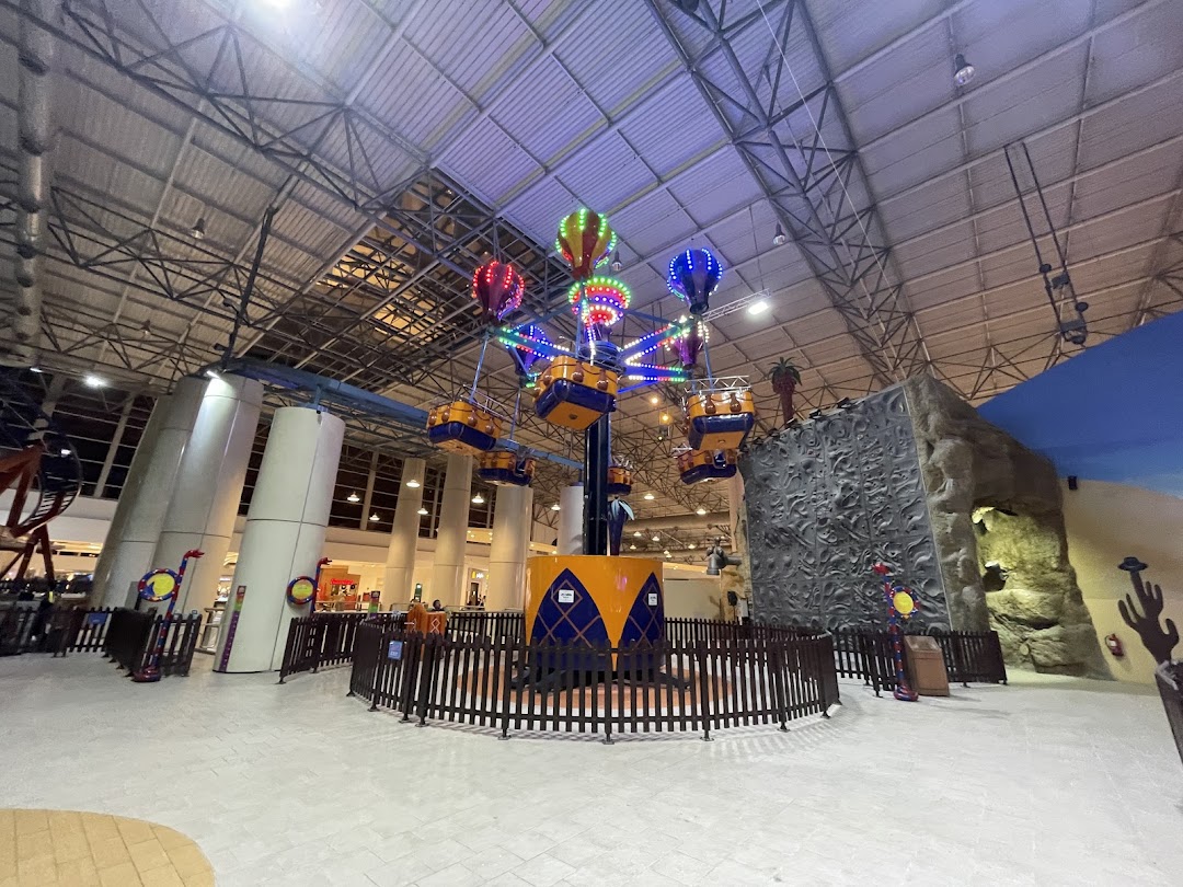 Indoor amusement park with a hot air balloon ride and a climbing wall.
