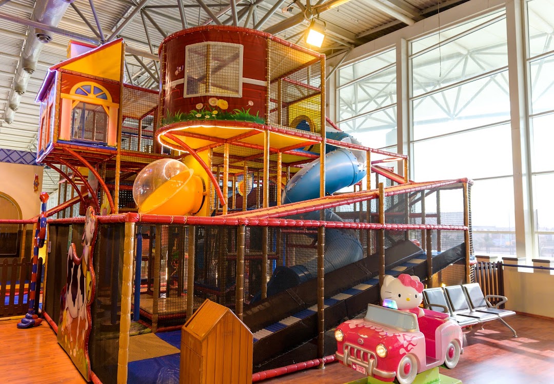 A vibrant indoor playground with slides, tunnels, and play structures for children.