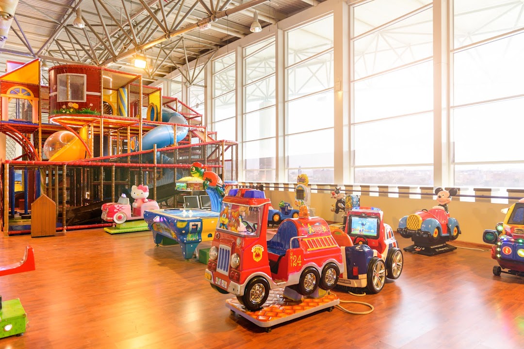 Indoor children's play area with a large climbing structure and various ride-on toys.