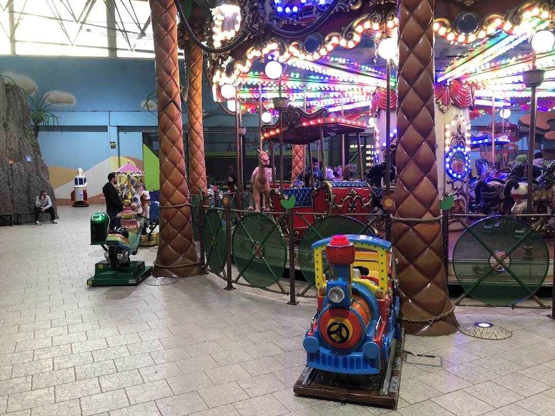 An indoor amusement area with a carousel, kiddie rides, and decorative elements.