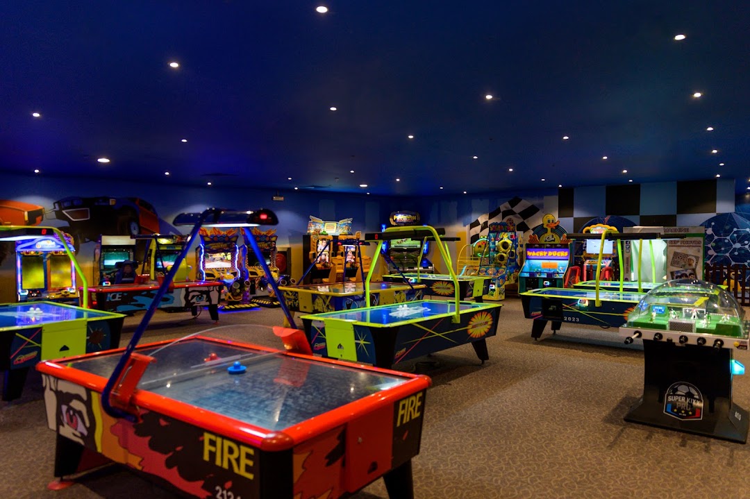 An indoor arcade with multiple air hockey tables and various video game machines.