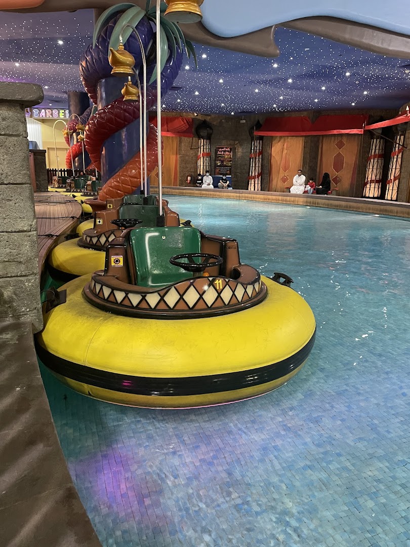 Yellow bumper boats are lined up in a pool with people sitting on the edge.