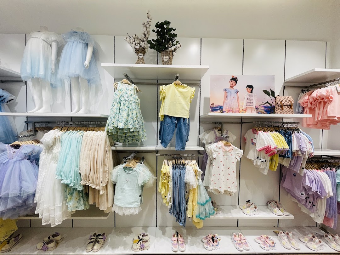 A well-organized display of children's clothing and shoes in various pastel colors.
