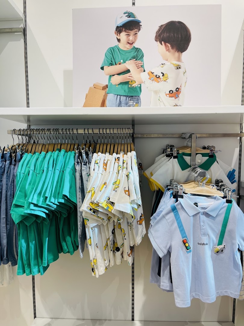 Children's clothing store display featuring colorful t-shirts and a promotional image of two boys.