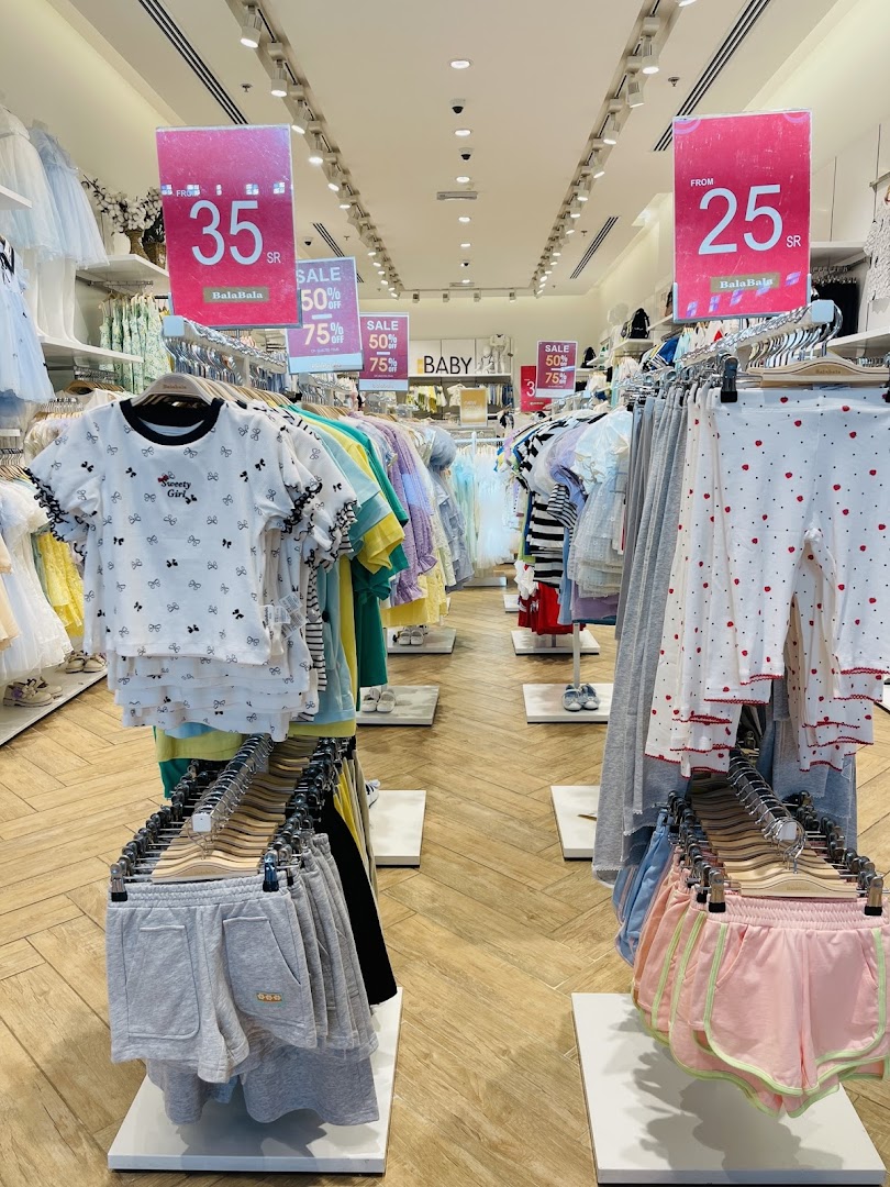 A well-lit store aisle displaying children's clothing with sale signs.