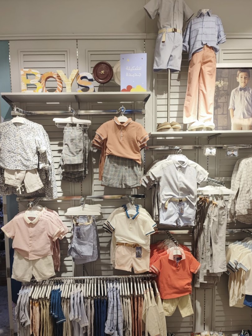A display of boys' clothing, featuring outfits on mannequins and racks of shirts and shorts.