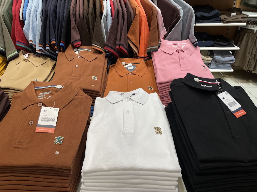 Neatly folded polo shirts in various colors are displayed in a retail store.