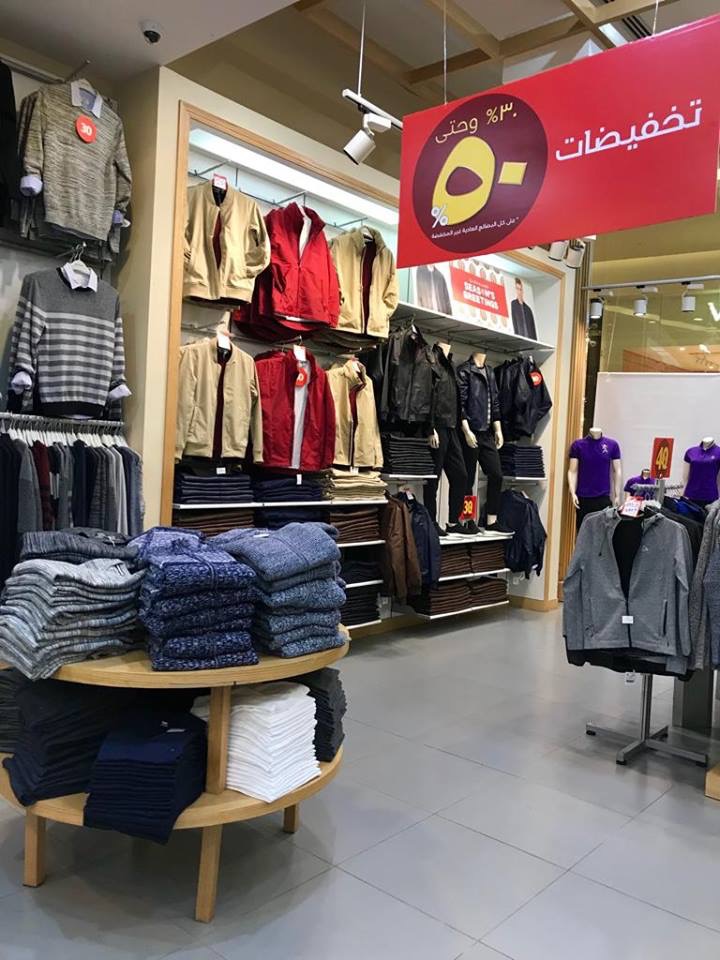 Interior view of a Giordano store showcasing men's jackets, sweaters, and folded shirts with a sale banner.