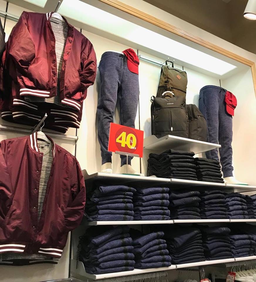 A display of men's casual wear including bomber jackets, sweatpants, and folded sweaters.