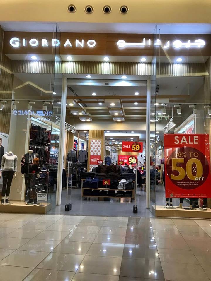 The entrance of a Giordano clothing store with mannequins and sale signs.
