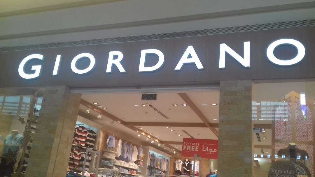 The exterior of a Giordano clothing store with illuminated signage and displays of apparel.