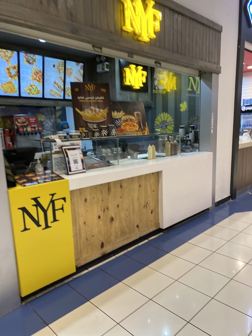 A food stall in a mall with bright yellow signage and a wooden counter.