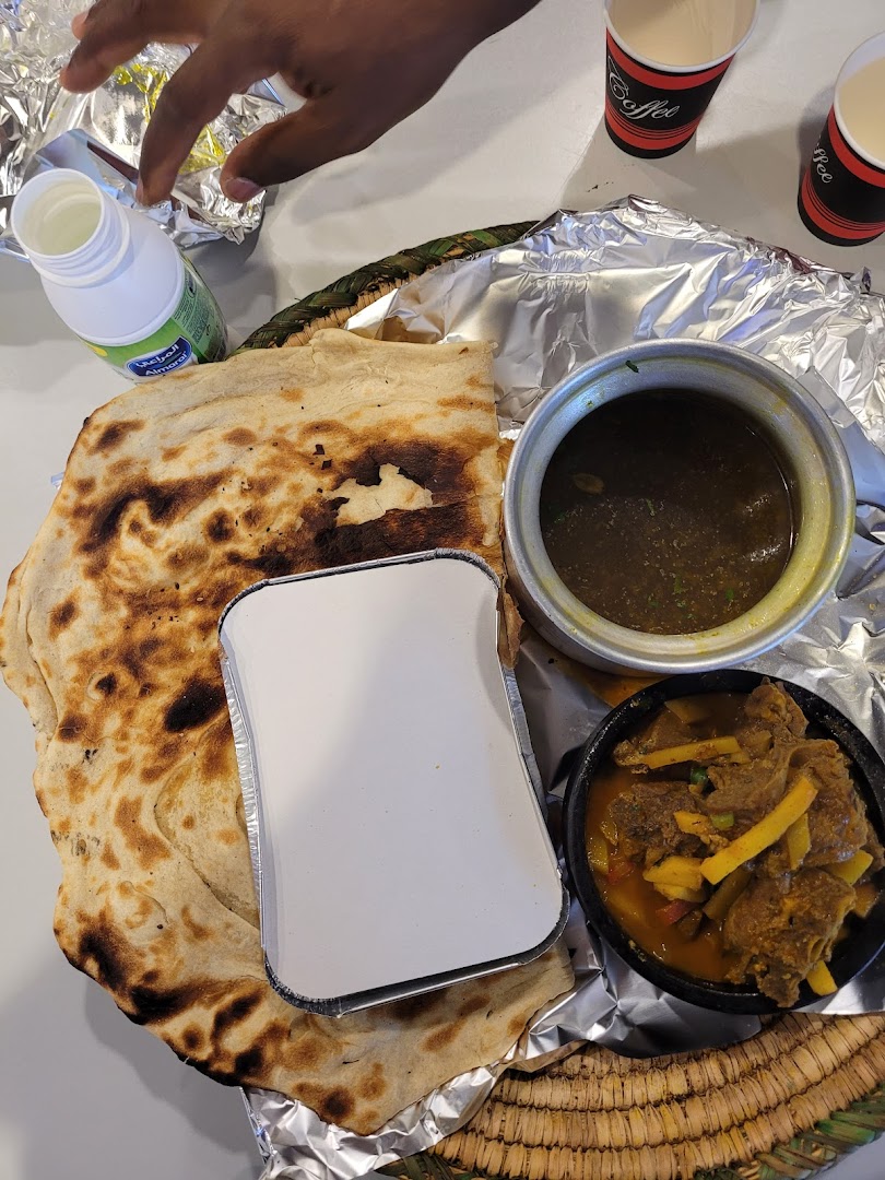 A delicious meal with flatbread, stew, and drinks served at a food court.