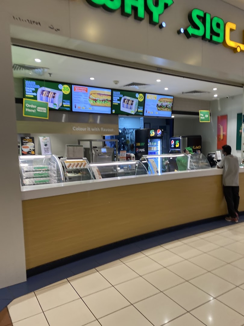 A Subway food counter with digital menus displaying sandwiches and drinks.