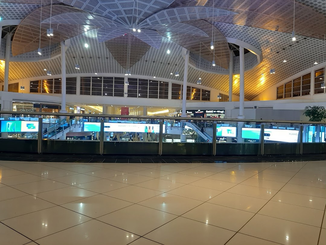 Interior view of a modern shopping mall with a distinctive ceiling and illuminated displays.