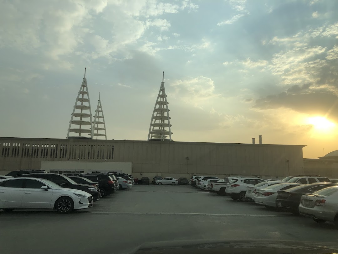 A parking lot filled with cars in front of a building with distinctive architectural towers.