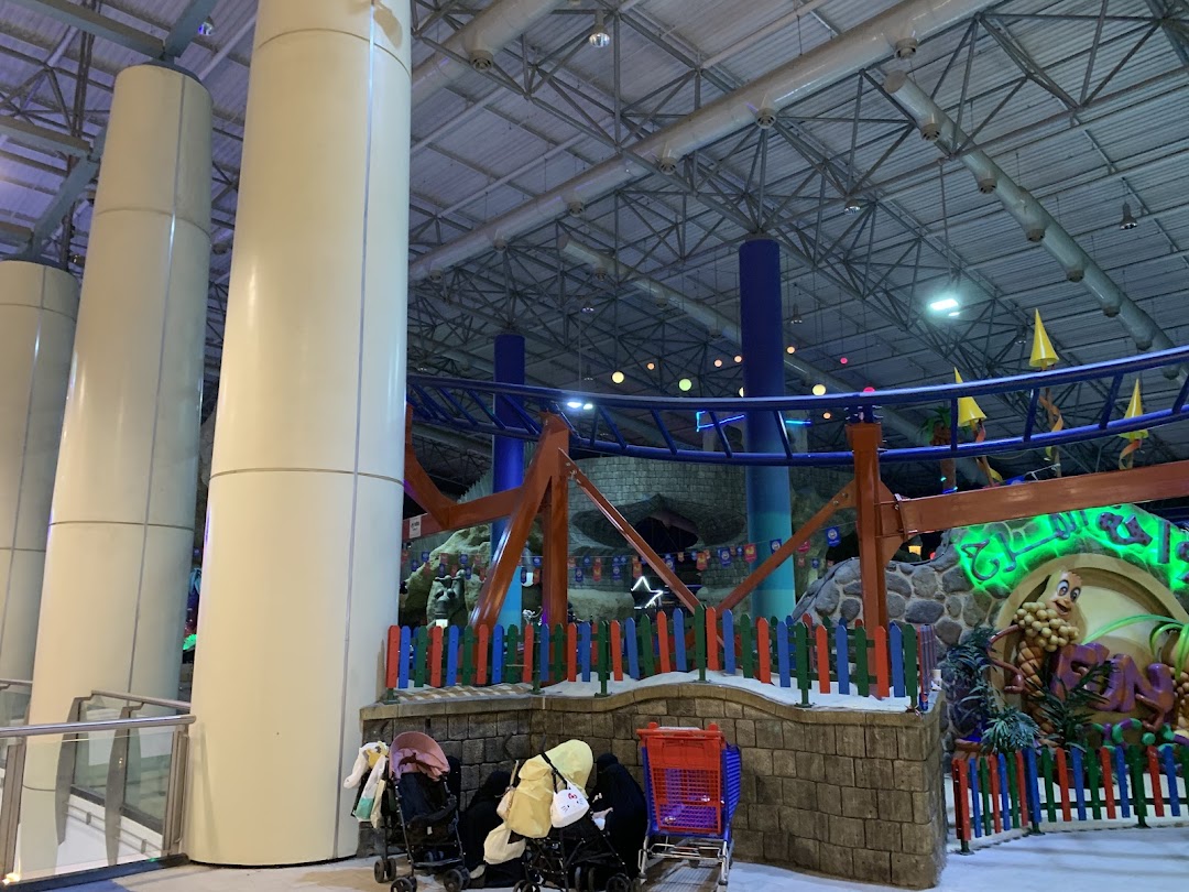 Indoor amusement park with a roller coaster, decorative elements, and strollers.