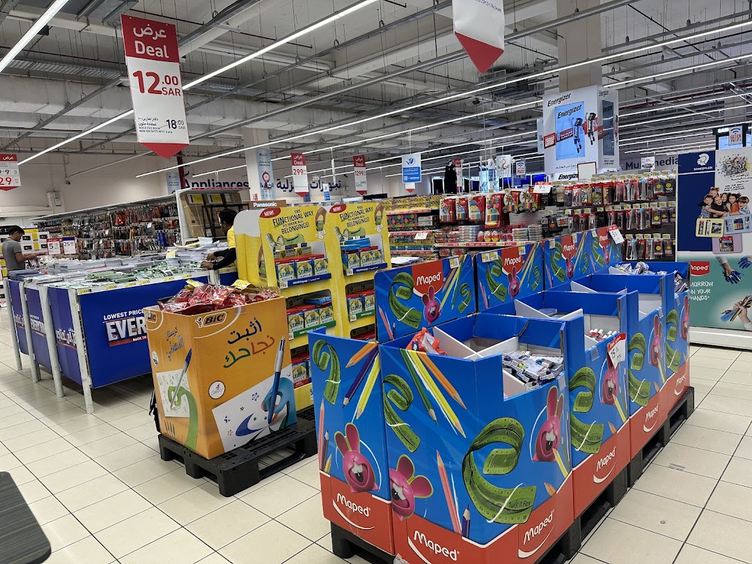 A retail store aisle displaying various stationery and school supplies, with promotional signs.