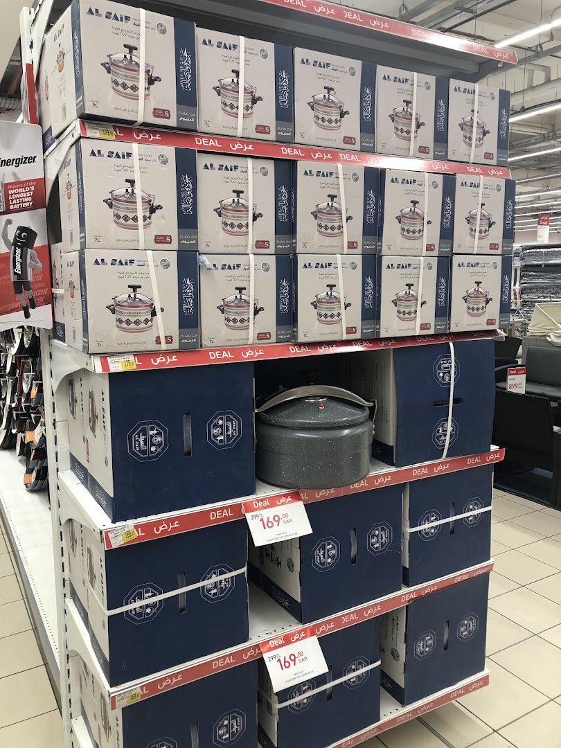 Shelves stacked with pressure cookers in boxes, with some individual units displayed.