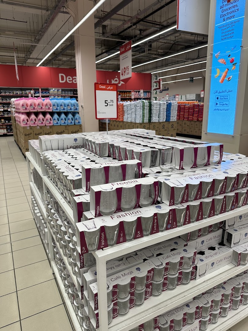 Shelves stocked with glassware, including tumblers and mugs, in a retail store.