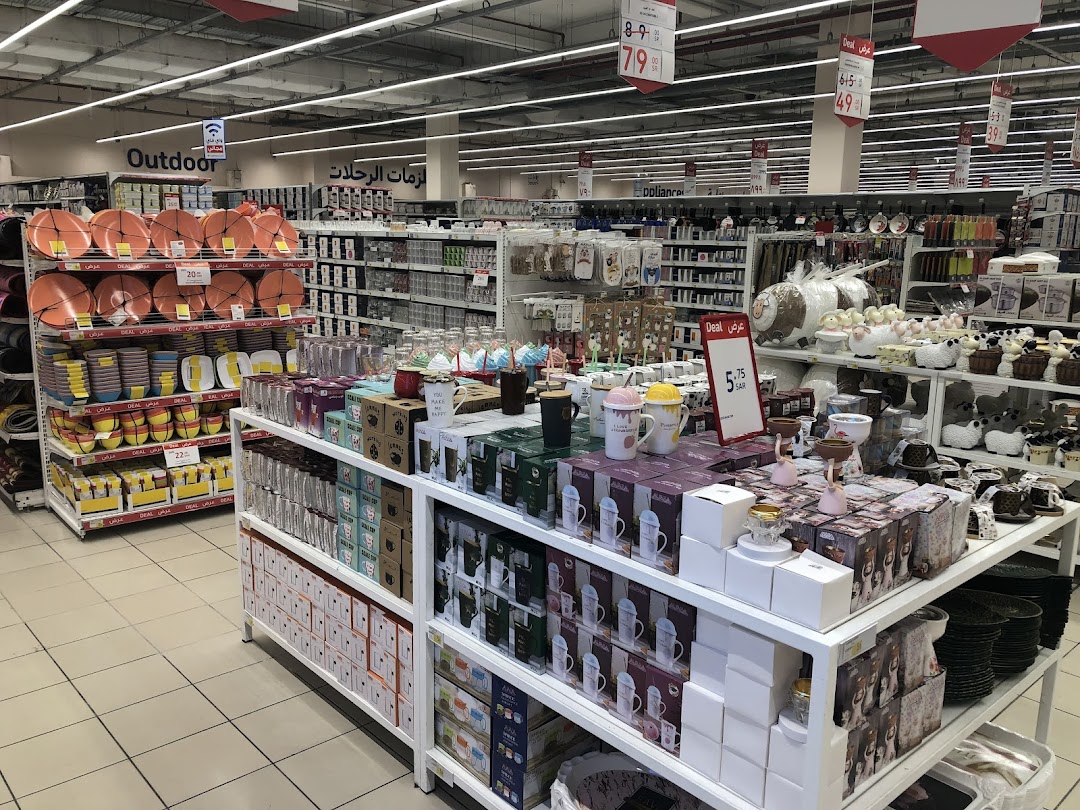 A wide aisle in a supermarket displaying kitchenware and home decor items on shelves.